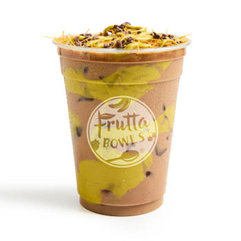 A Dubai Chocolate Mocha from Frutta Bowls, served in a clear cup with bold green swirls, filled with a chocolate-blended drink and ice, and topped with shredded toppings, cacao nibs, and a drizzle of green nut butter.