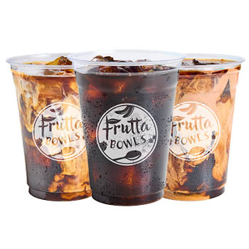 Three clear plastic cups of iced drinks with Frutta Bowls logos, featuring a dark center drink and two cream-swirled drinks behind it on a light gray background.
